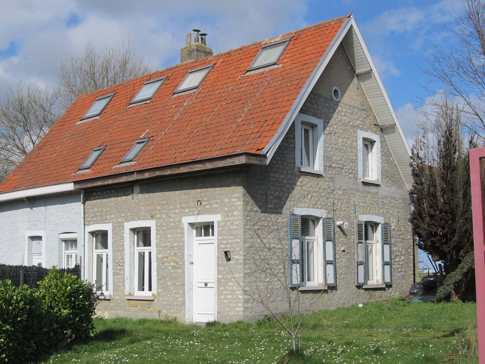 Woning met een rood pannendak en dakramen tussen het groen